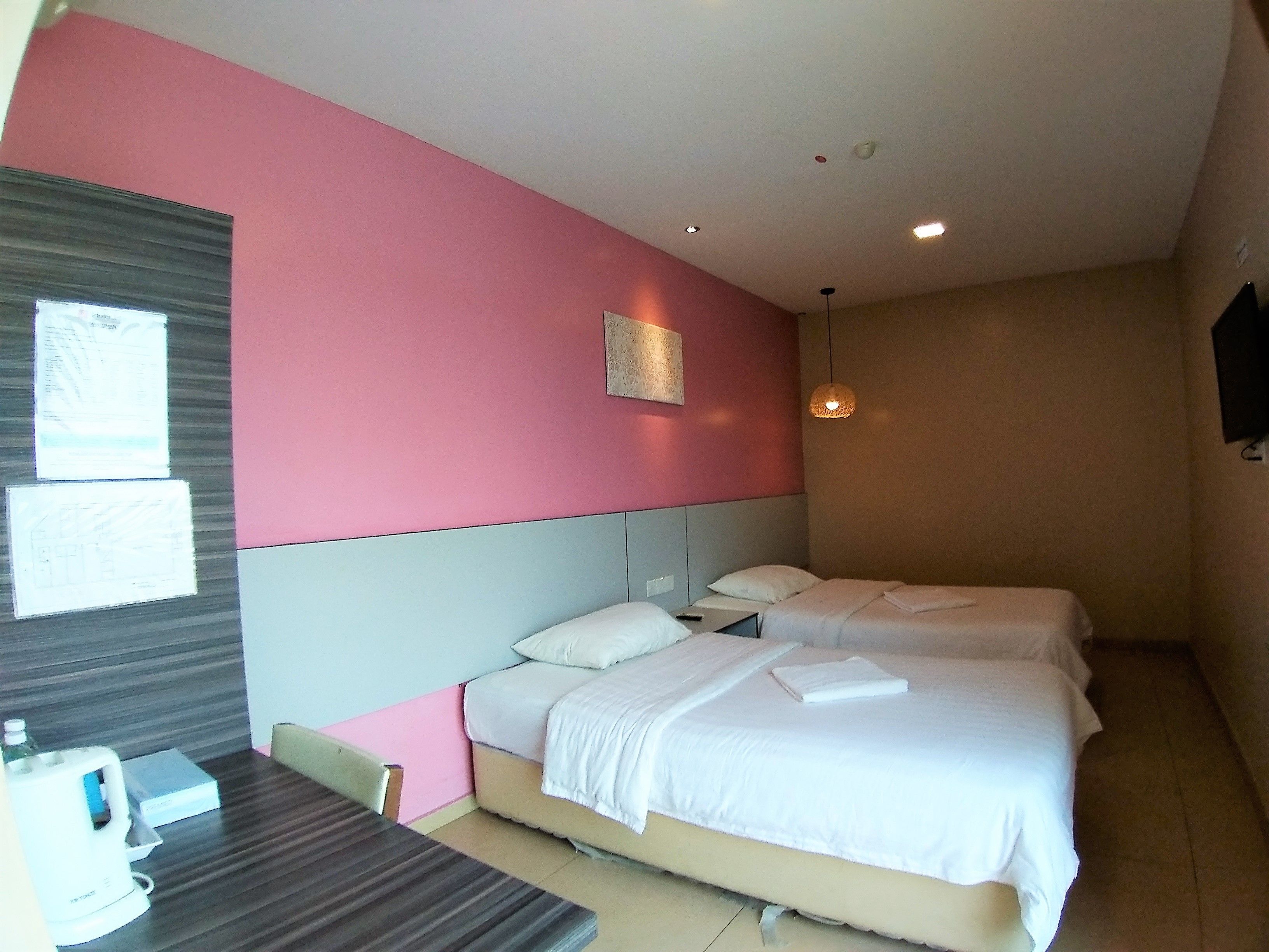 Ein Hotelzimmer mit zwei Betten, einem Schreibtisch und einem Stuhl.