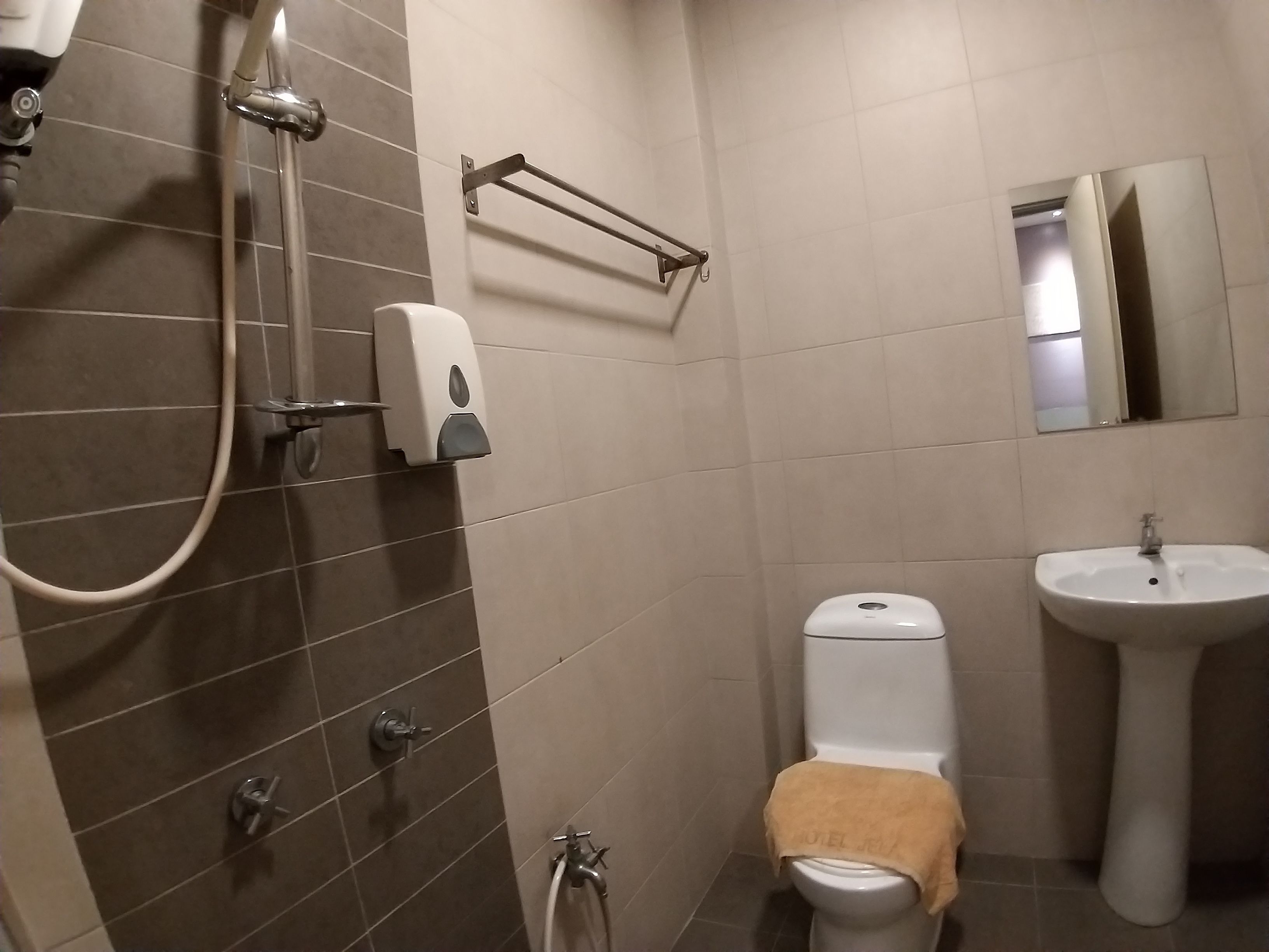 Une salle de bain équipée d’une douche, de toilettes, d’un lavabo et d’un porte-serviettes.