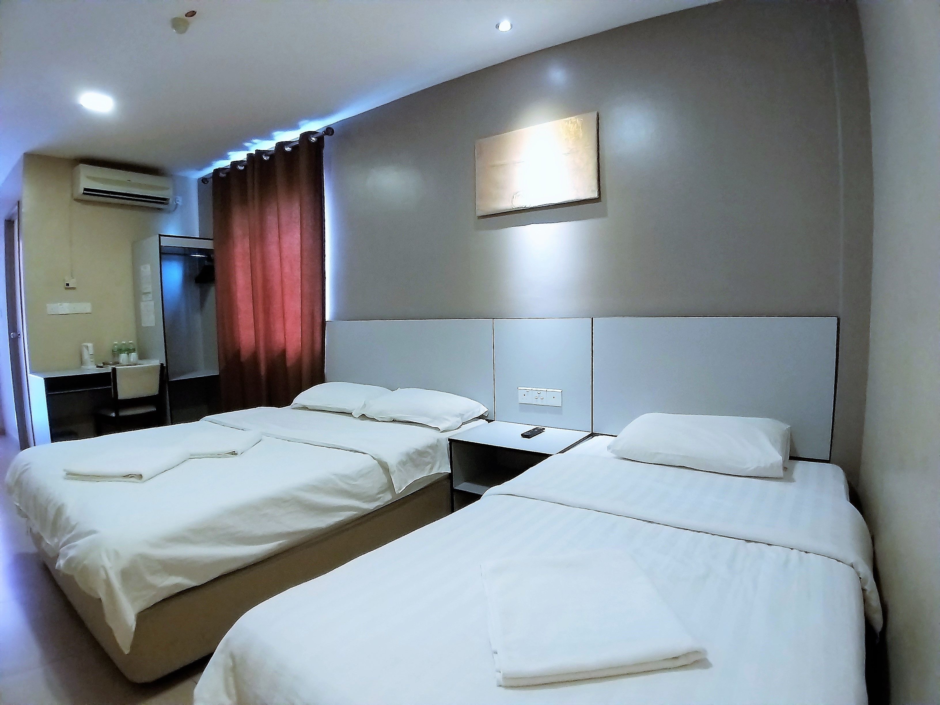 Habitación de hotel con dos camas, un escritorio, una silla, un aire acondicionado y un espejo.