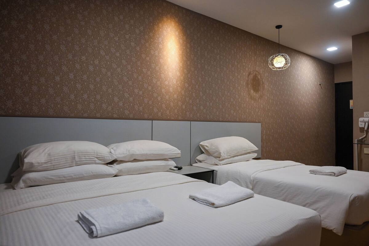 Ein Hotelzimmer mit zwei Betten, einem Kopfteil und einer Wandleuchte.