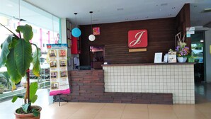A hotel reception area with a modern design, featuring a reception desk, a large potted plant, and a wall clock. - Hotel Jelai Temerloh (Temerloh)