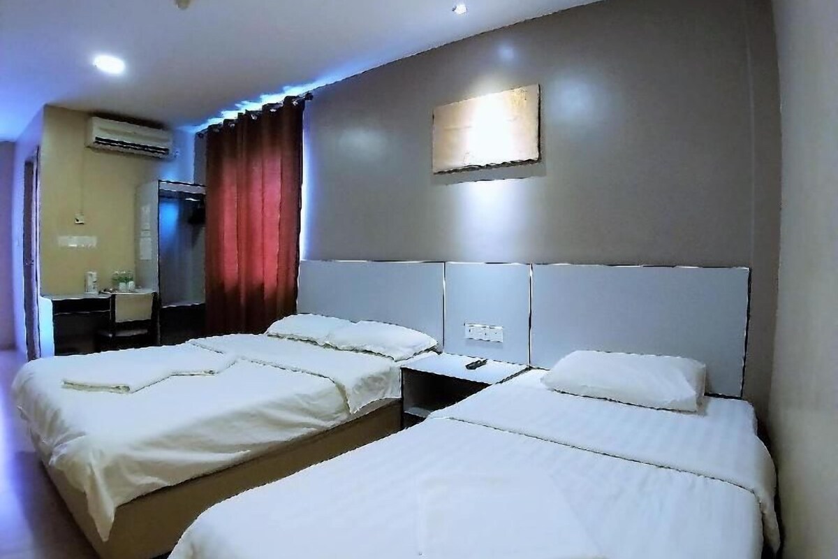 A hotel room with two beds, a desk, a mirror, and an air conditioning unit.
