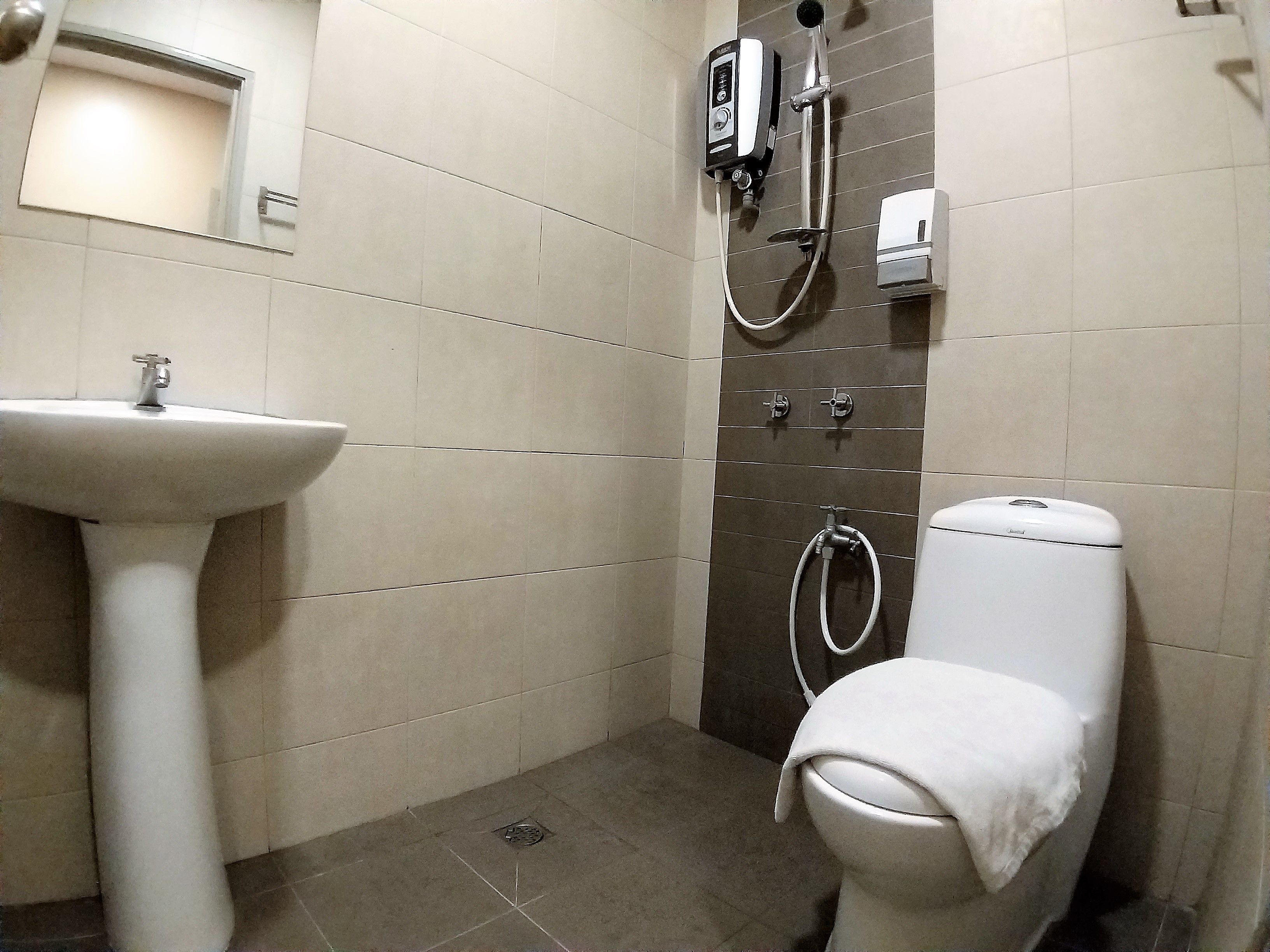 A bathroom with a pedestal sink, a toilet, and a shower unit.