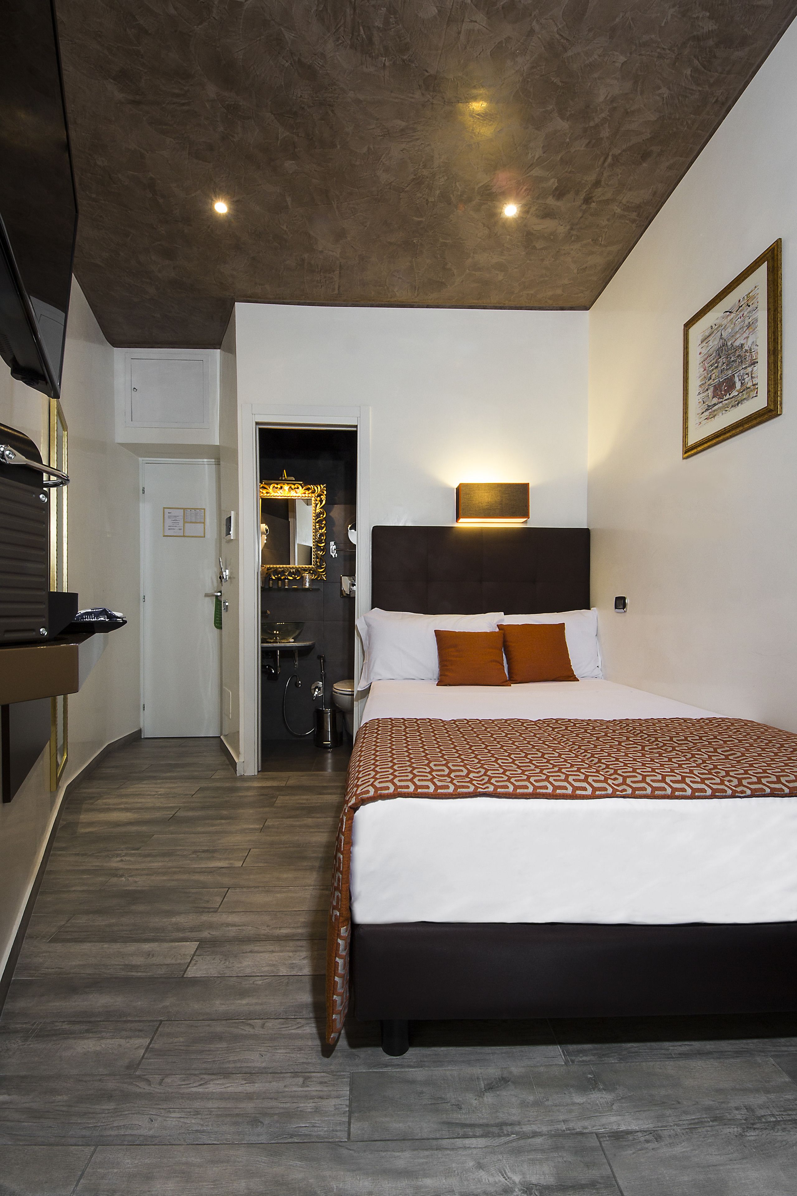 Una habitación de hotel con una cama grande, una mesita de noche, un espejo y una puerta que da a un baño.