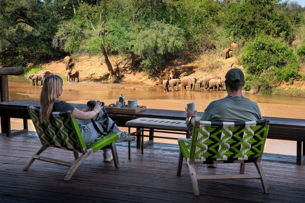 Une terrasse dotée de deux fauteuils à bascule, d’où l’on peut admirer une rivière et apercevoir, au loin, des éléphants.