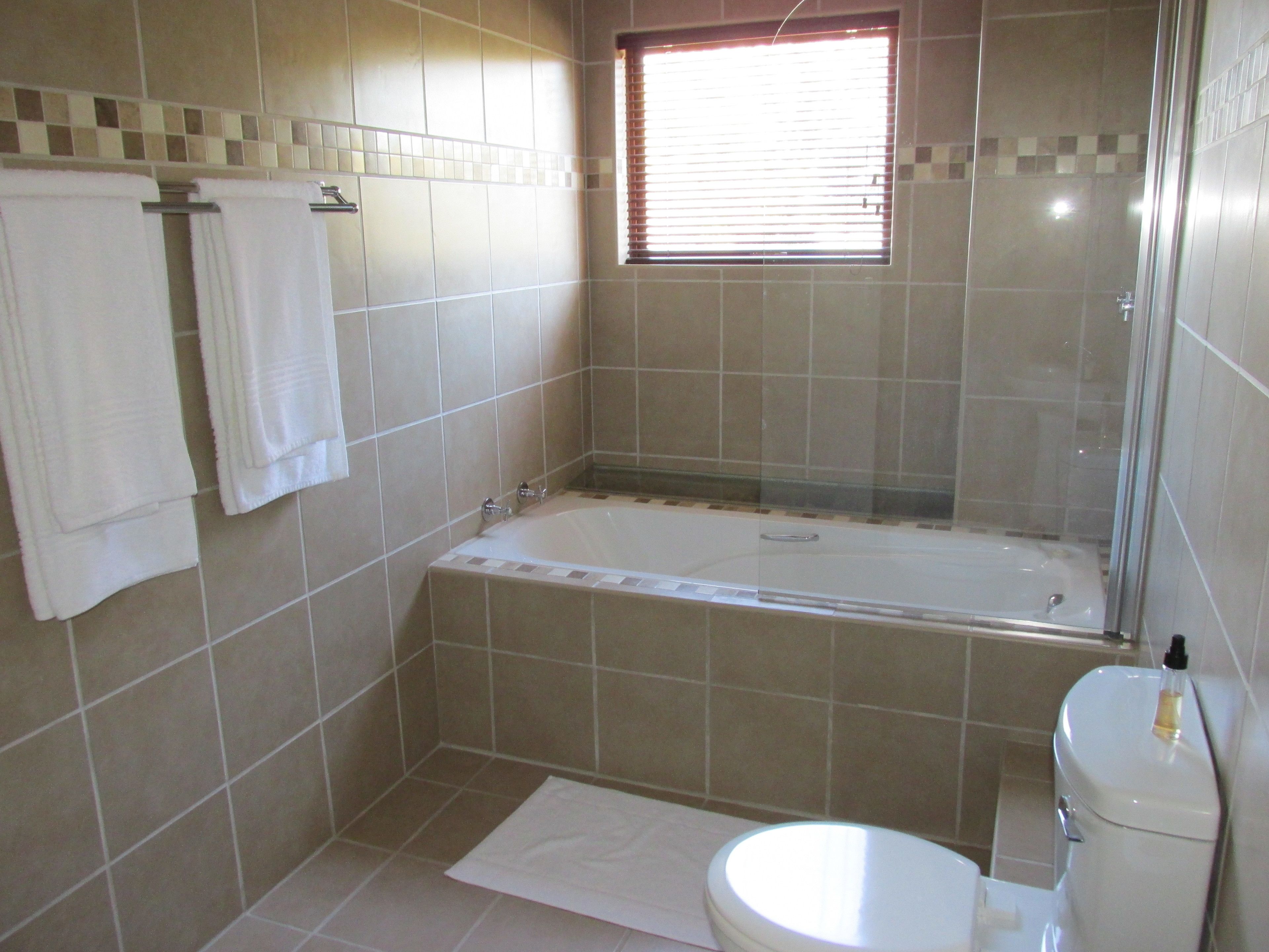 A bathroom with a bathtub, toilet, and a window.