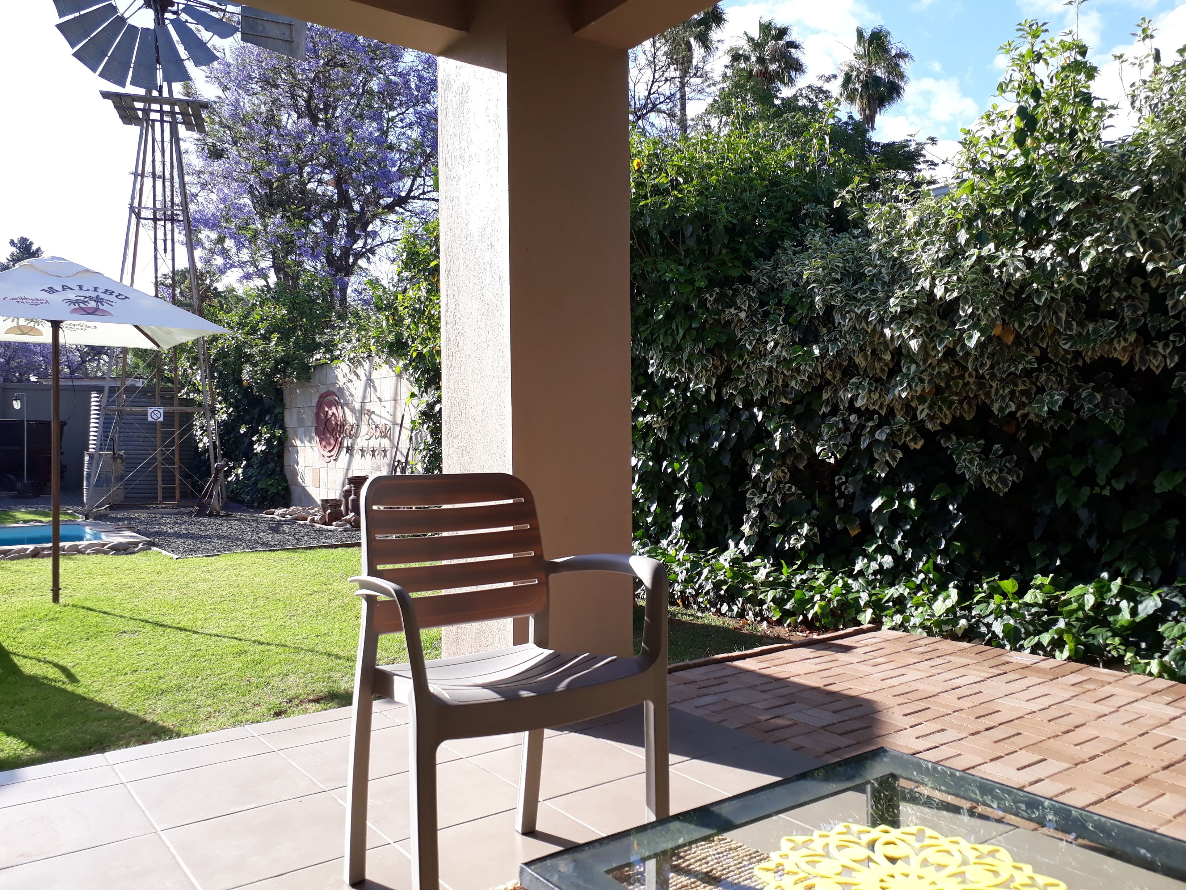 Un patio con una silla, una mesa de vidrio y un molino en el fondo.