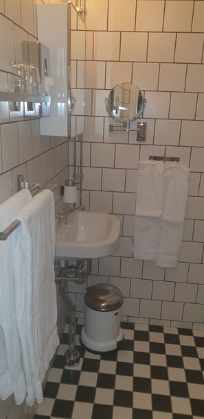 A bathroom with a sink, mirror, toilet, and checkered floor tiles.
