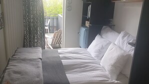 Un dormitorio con cama, mesita de noche, armario y vistas al balcón exterior.