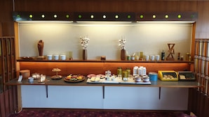 Una barra de desayuno con diferentes alimentos, salsas y jarrones decorativos.
