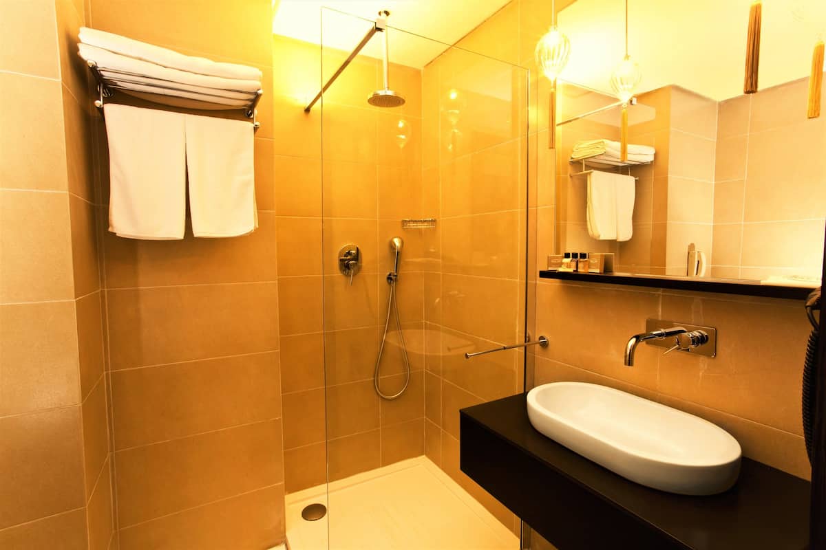 Ein modernes Badezimmer mit einer gläsernen Duschkabine, einem weißen Waschbecken und einer schwarzen Arbeitsplatte.
