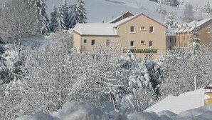 A building with a sign that reads "RESTAURANT BAR" surrounded by snow-covered trees and hills.