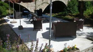 An outdoor patio area with wicker furniture, stone walls, and a stone archway.