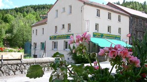 A hotel with a restaurant bar, surrounded by greenery and a stone wall.