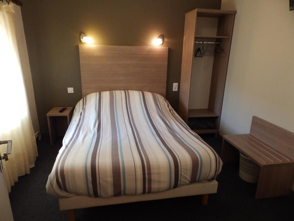 A bed with a striped pillow, a bedside table, a wooden bench, and a wardrobe.