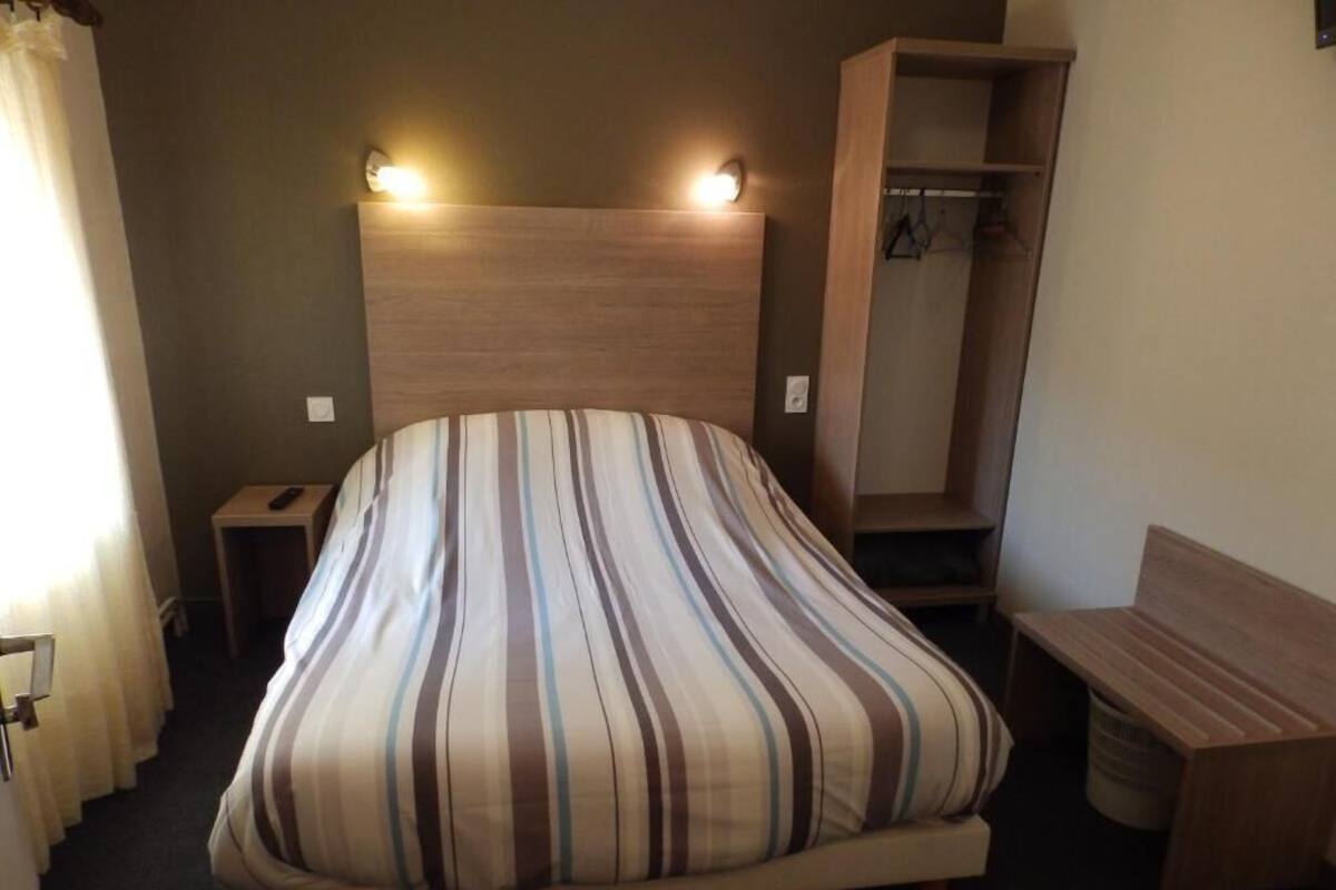 A bed with a striped pillow, a bedside table, a wooden bench, and a wardrobe.