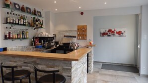 A bar area with a stone counter, stools, and a variety of liquor bottles.