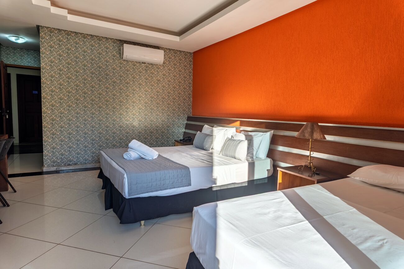 A hotel room with two beds, a desk, and a chair.