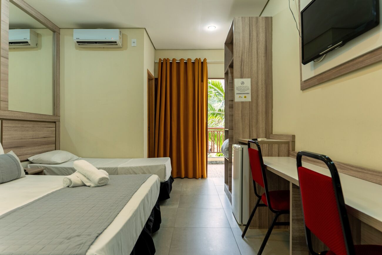 Habitación de hotel con dos camas, un escritorio, una silla, un televisor y un equipo de aire acondicionado.