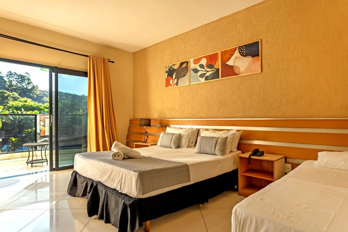 Habitación de hotel con cama, mesitas de noche, cortinas y vistas al exterior.