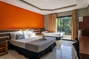 Une chambre d’hôtel avec deux lits, un coin repas et un balcon avec des rideaux.