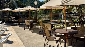 Ein Patio-Bereich mit Sitzgelegenheiten im Freien, darunter Stühle und Tische, beschattet durch Sonnenschirme.