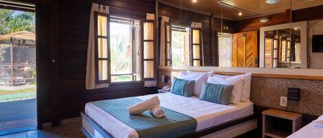 A hotel room with a large bed, a small bedside table, a mirror, and a view of the outdoors.