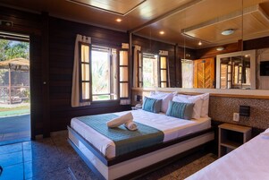 Una habitación de hotel con una cama grande, una mesita de noche pequeña, un espejo y vistas al exterior.