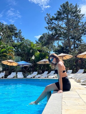 A poolside area with lounge chairs and umbrellas, surrounded by trees and a clear sky. - Hotel Green Hill (Juiz de Fora)