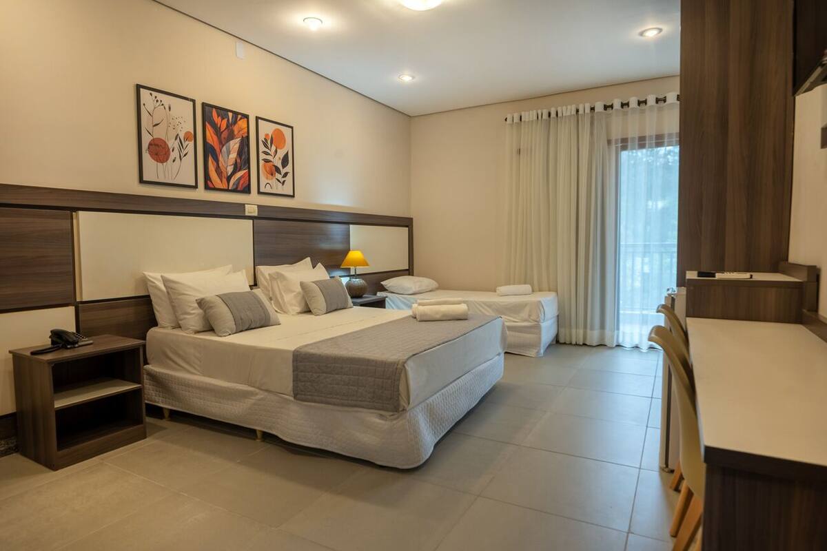 Una habitación de hotel moderna con una cama grande, mesitas de noche, un escritorio y una silla.
