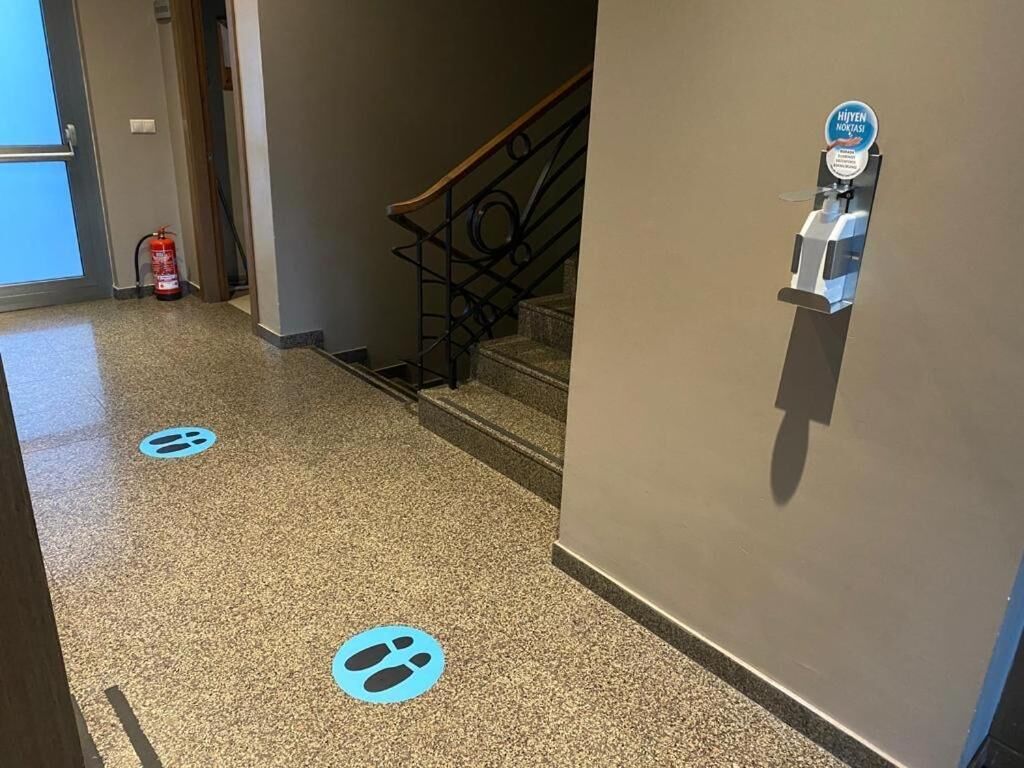 A hotel hallway with a fire extinguisher, a hand sanitizer station, and a staircase.