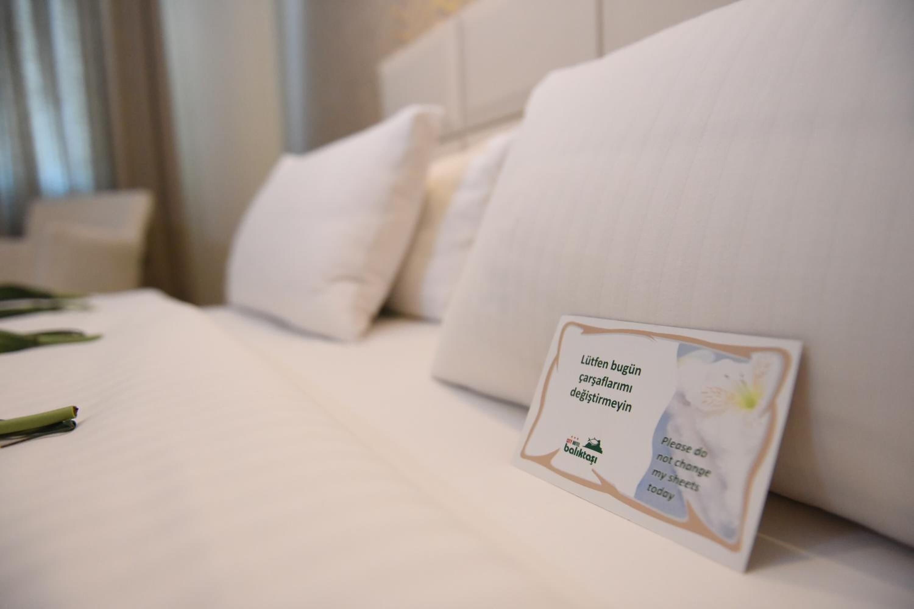 Une chambre d’hôtel avec un lit bien fait, du linge de lit blanc et une carte posée sur le lit.