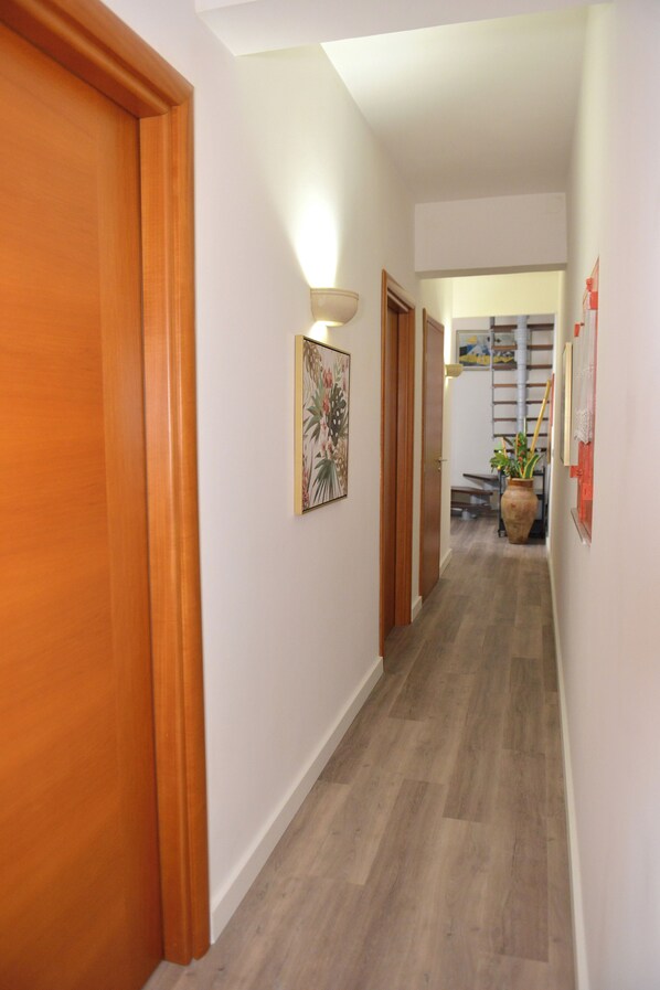 A hallway with wooden doors, a wall-mounted light fixture, and a potted plant.