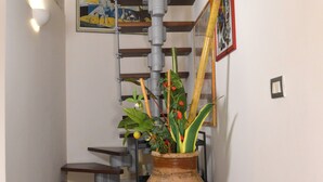 Una escalera de diseño moderno, un jarrón grande con plantas y obras de arte en las paredes.