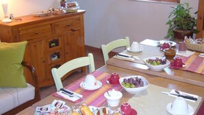 Un comedor con un armario de madera, una mesa dispuesta con platos, tazones y una planta en maceta.
