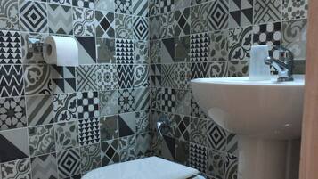 A bathroom with patterned tiles, a toilet, a sink, and a towel.