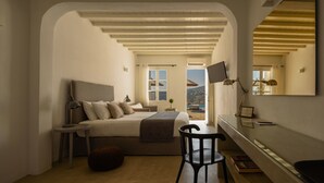 A bedroom with a bed, a desk, a chair, and a large mirror. - Cova Mykonos Suites (Mykonos)