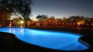 A swimming pool with a wooden deck and a metal fence. - Dinkweng Safari Camp (Vaalwater)