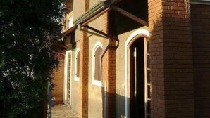 A brick building with arched doorways and a stone pathway leading to the entrance. - Pousada Nasa (São Bento do Sapucaí)