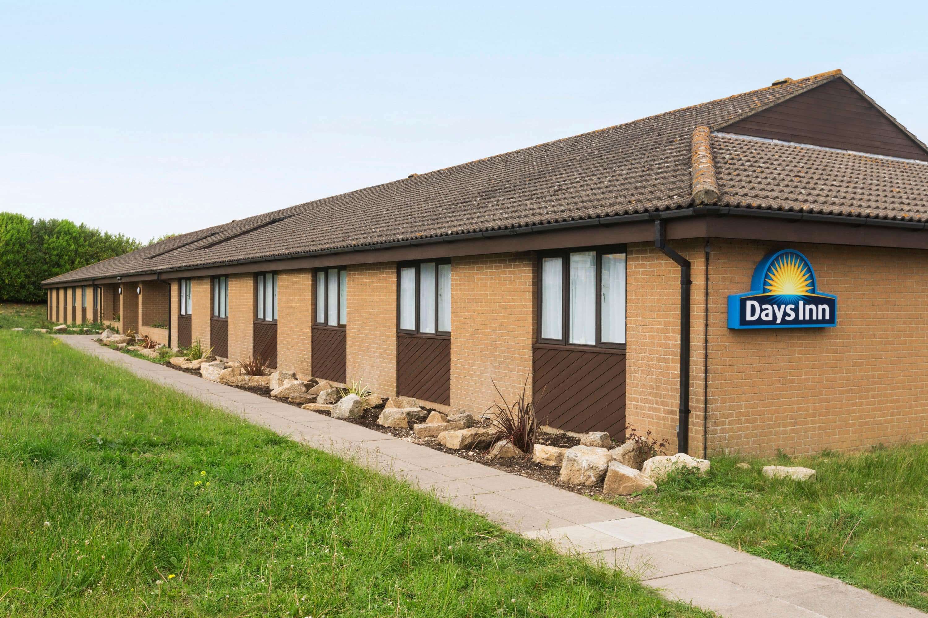 A Days Inn building with a brick facade, a tiled roof, and a signboard.