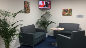 Un área de espera con dos sofás, una mesita y un televisor en la pared.