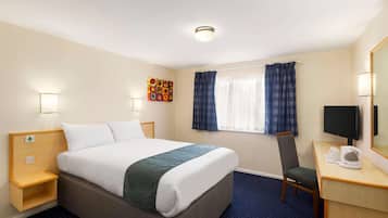 A hotel room with a bed, bedside table, chair, desk, TV, and a window with curtains.