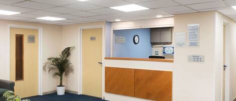 A reception area with a reception desk, a clock, and signs indicating room availability.