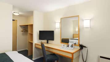 Ein Hotelzimmer mit einem Bett, einem Schreibtisch mit Stuhl, einem Fernseher, einem Spiegel, einem Telefon und einem Kleiderschrank.