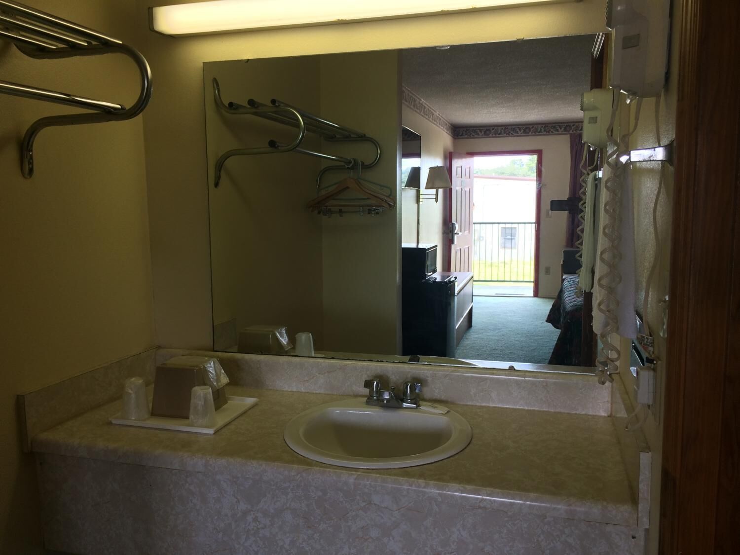 Une salle de bain équipée d’un lavabo, d’un miroir, d’un porte-serviettes et offrant une vue sur un balcon.