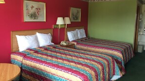 A hotel room with two beds, a wooden headboard, a bedside table with a lamp, and a small table with a telephone. - Western Motel of Camilla (Camilla)