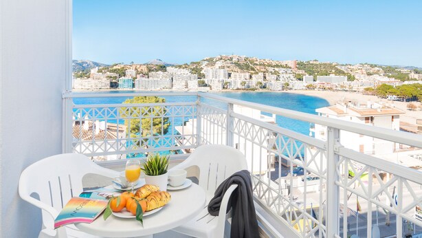 Un balcon avec une table préparée pour le petit-déjeuner, offrant une vue sur le paysage urbain de la côte.