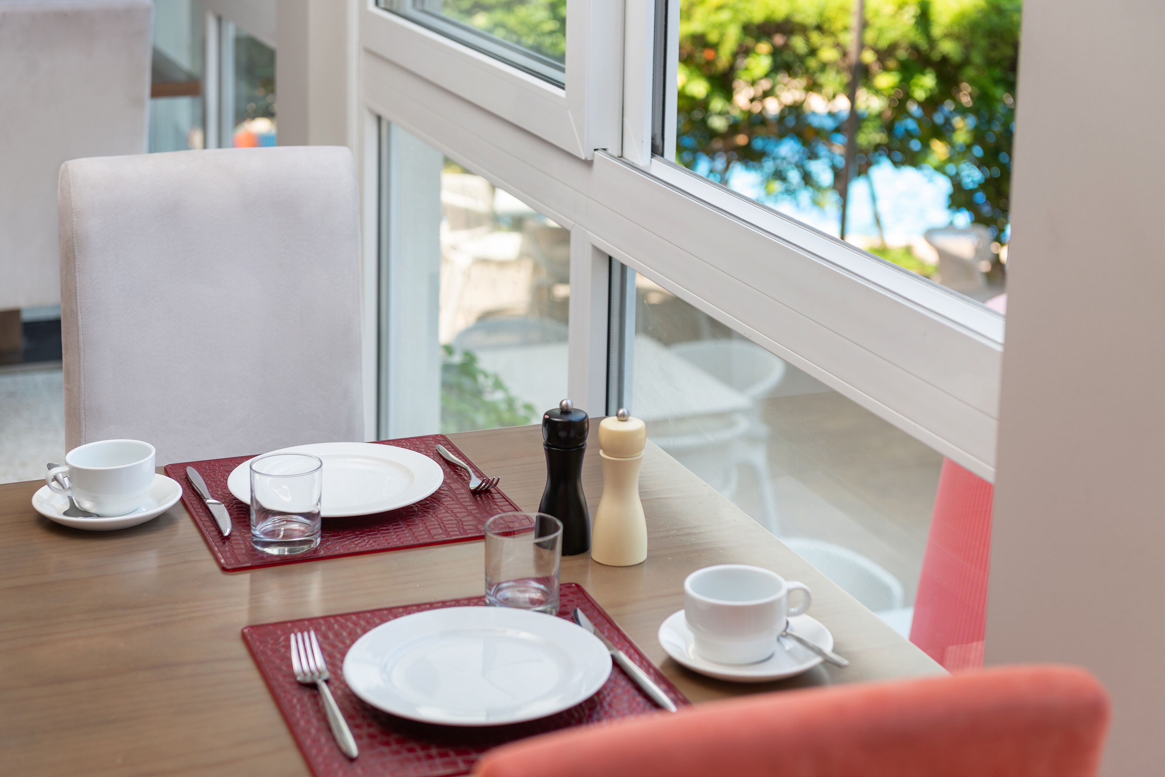 Una mesa de comedor dispuesta con platos, cubiertos, vasos y salero y pimentero.