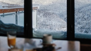 A mountain view through a window with a table in the foreground.