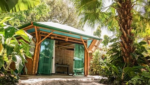 A small, open-air structure with bamboo walls and a green roof, surrounded by lush tropical vegetation. - Pousada Treze Luas (Paranaguá)
